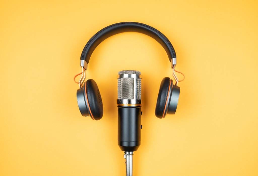 podcasting concept, directly above view of headphones and recording microphone on orange background